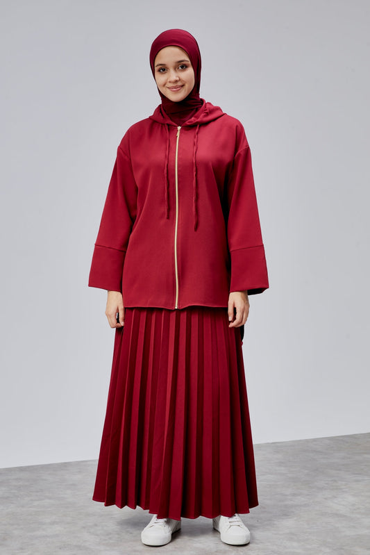 Woman wearing a red outfit with a matching hijab on a gray background