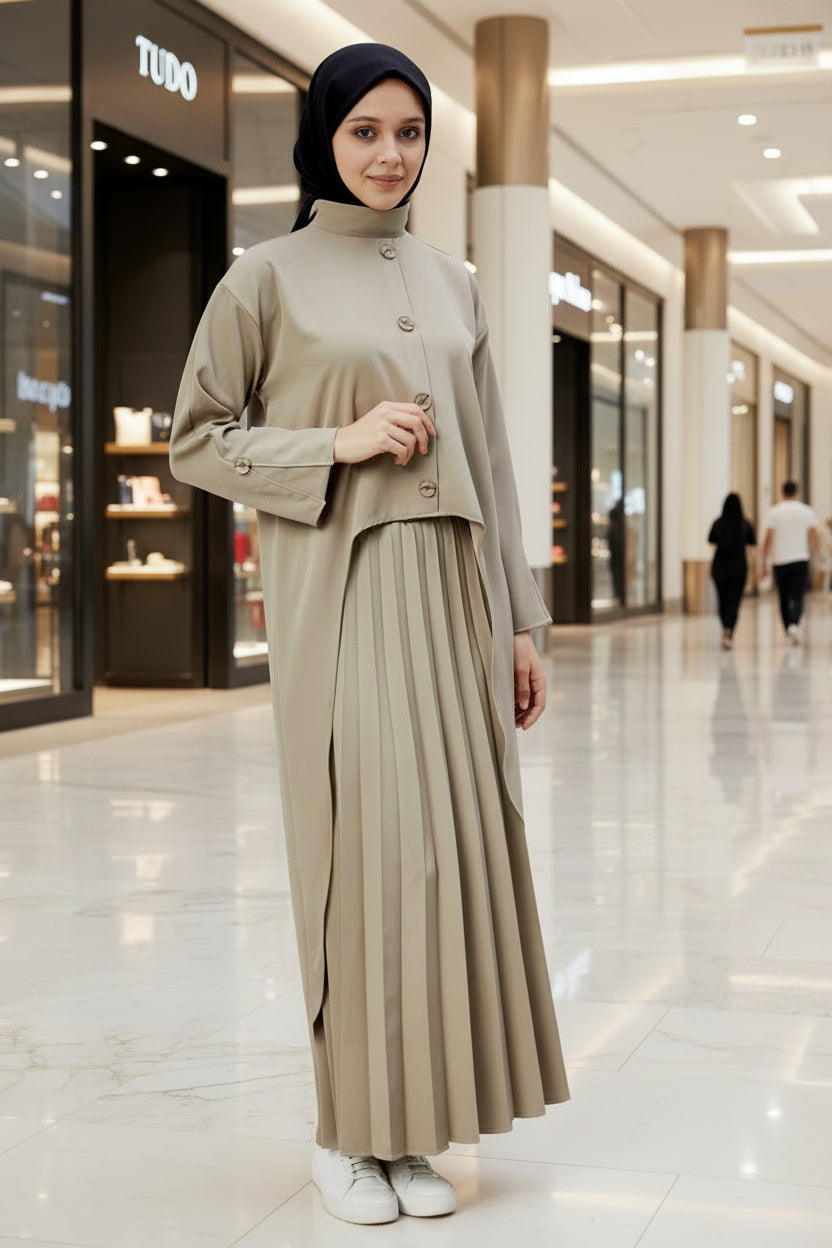 Woman wearing a beige outfit with a pleated skirt on a plain background