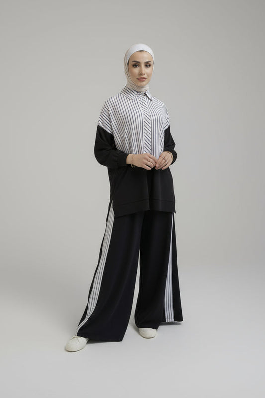 Woman wearing a black outfit with white stripes on a plain background