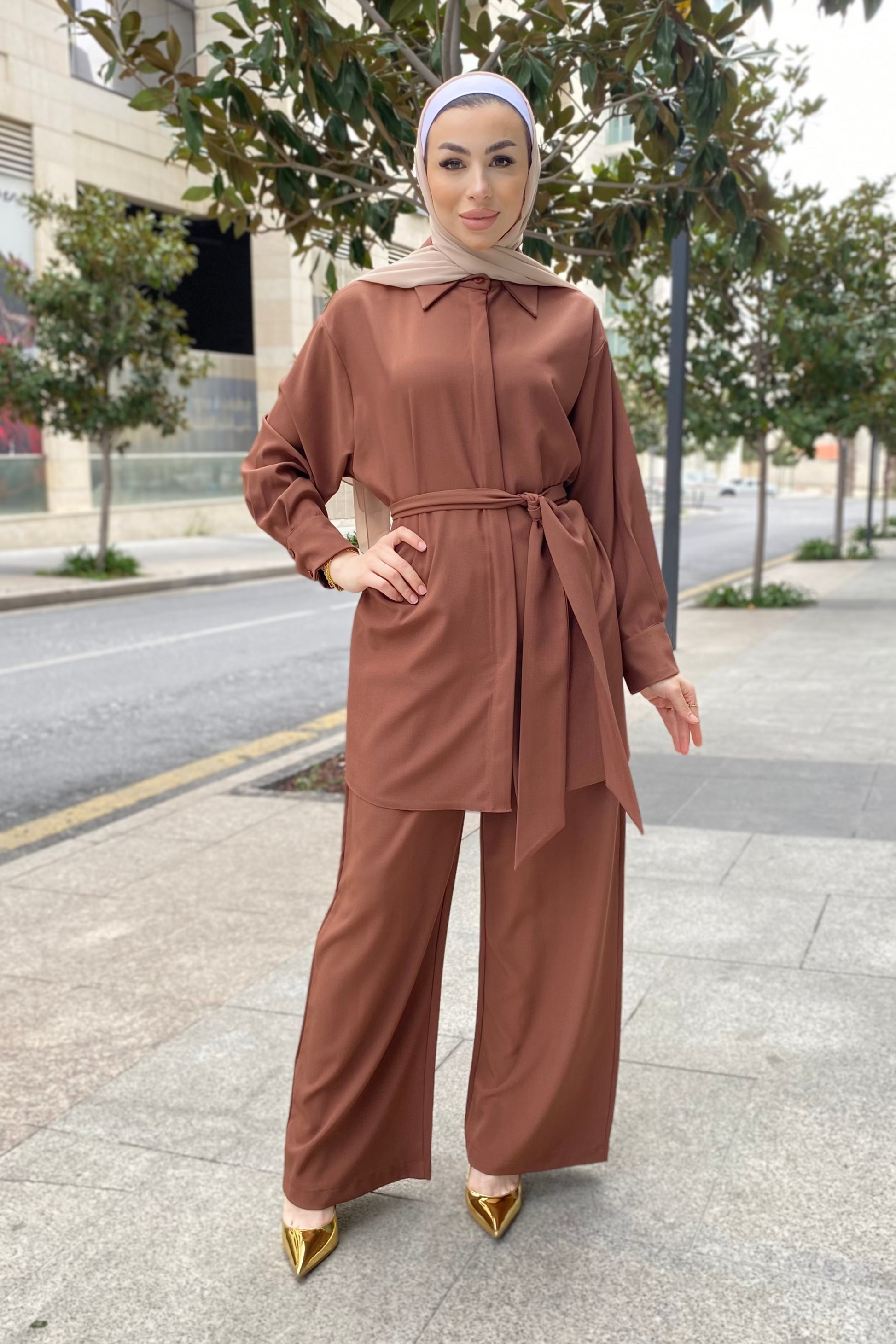 Woman in a brown outfit standing on a city street.