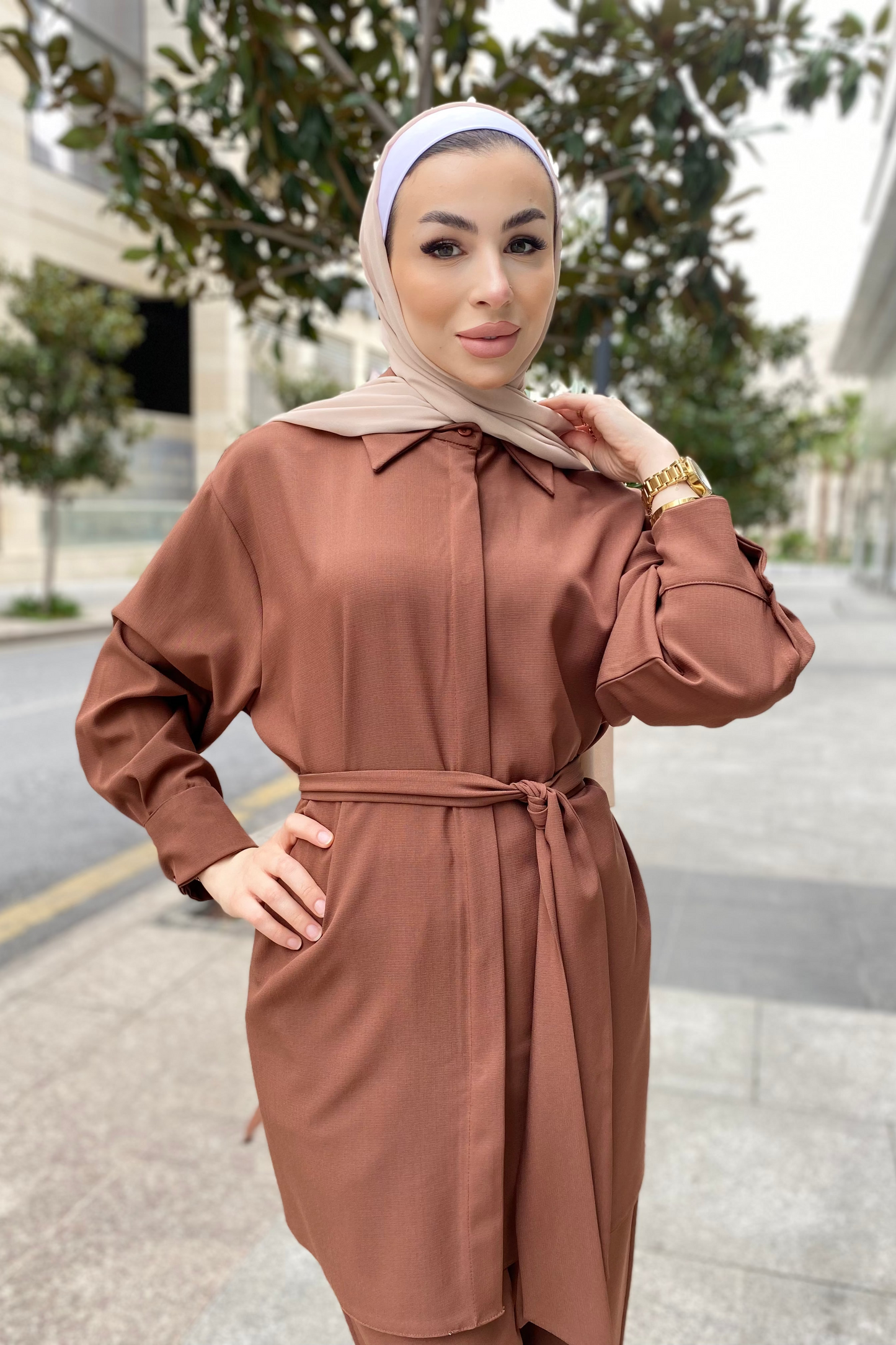 Woman wearing a brown outfit with a headscarf on a street.