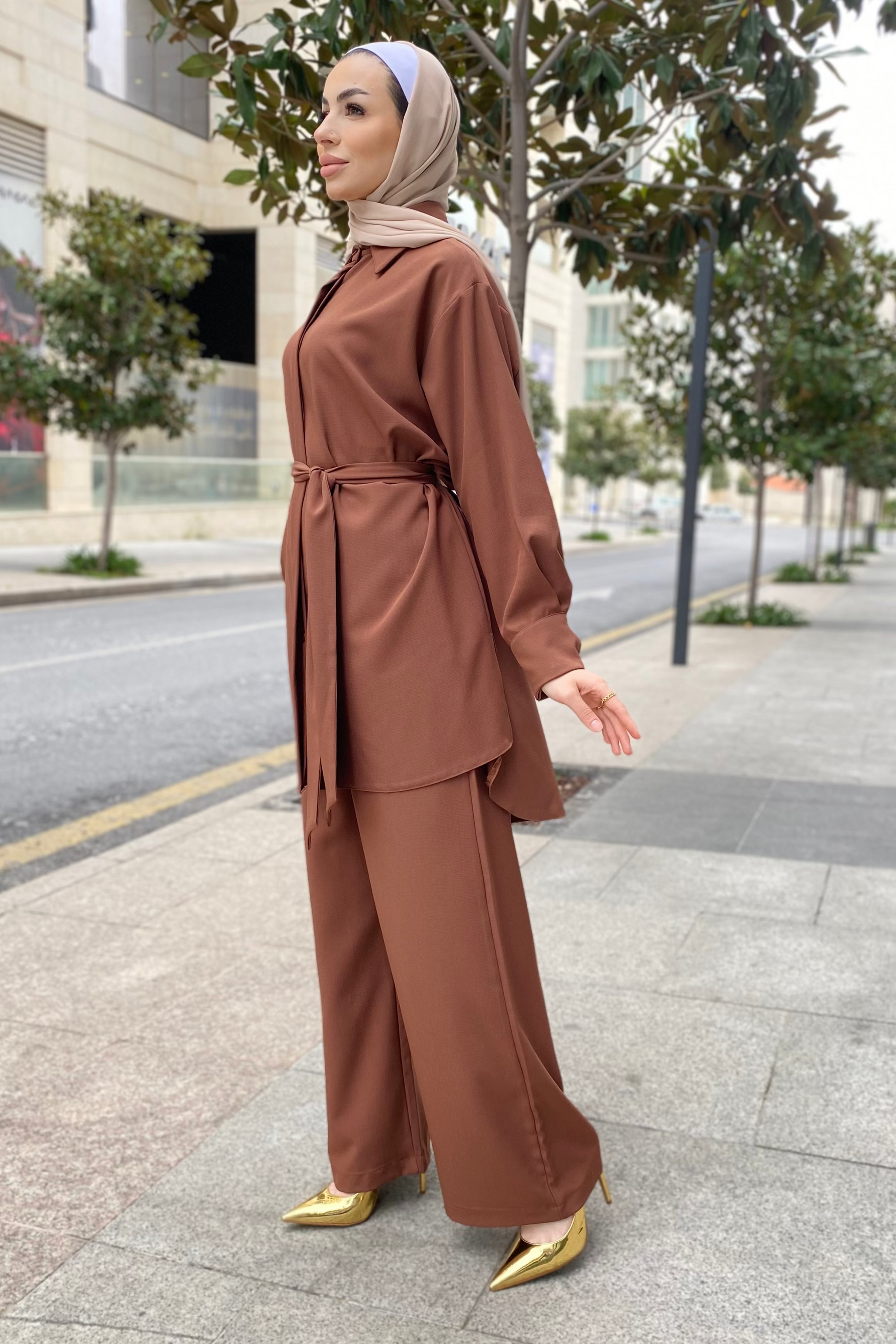 Woman in a brown outfit standing on a city street