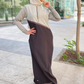 Woman wearing a gray top and brown pants with a hijab in an urban setting.