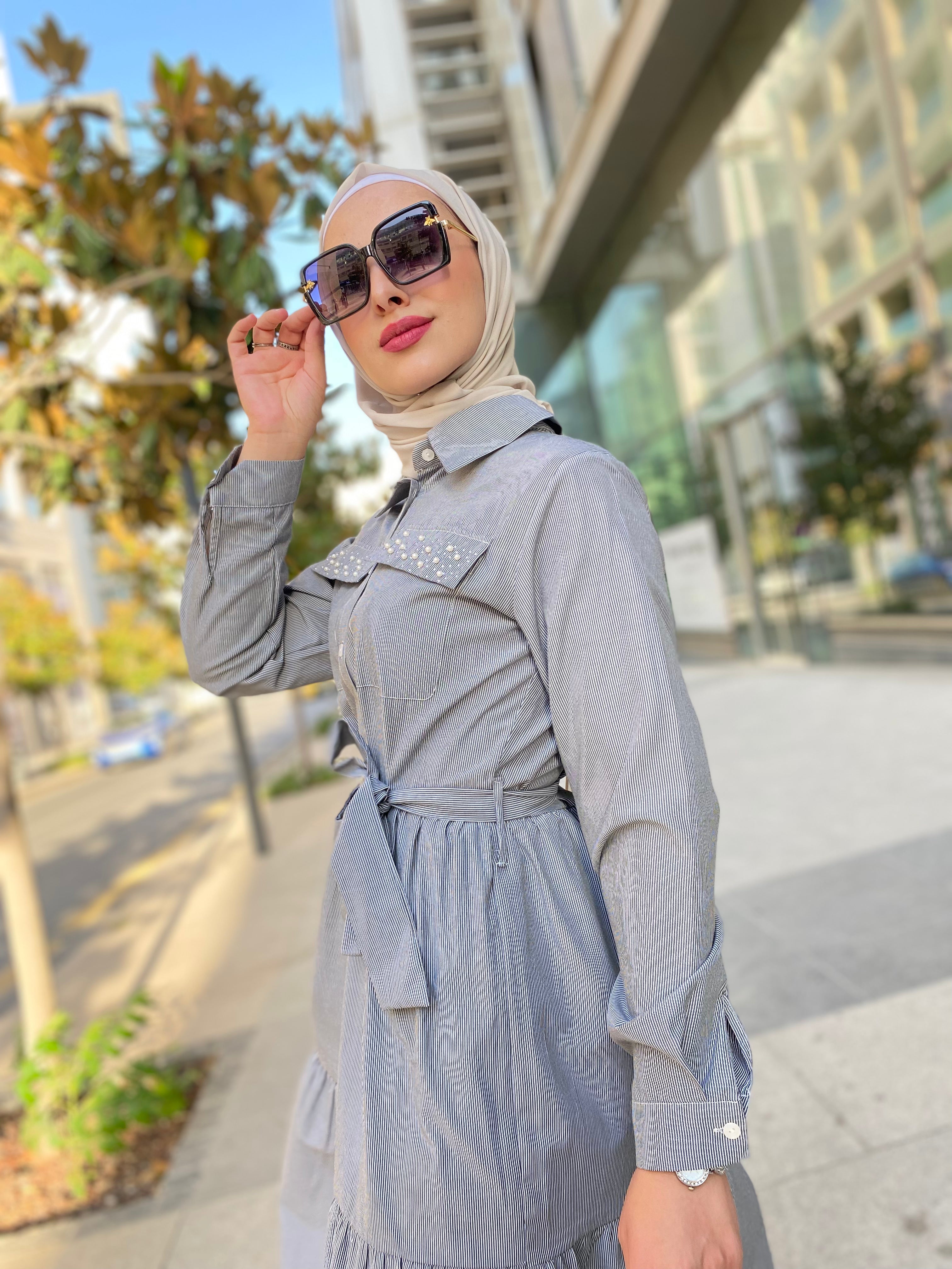 Woman in a gray outfit with sunglasses on a city street