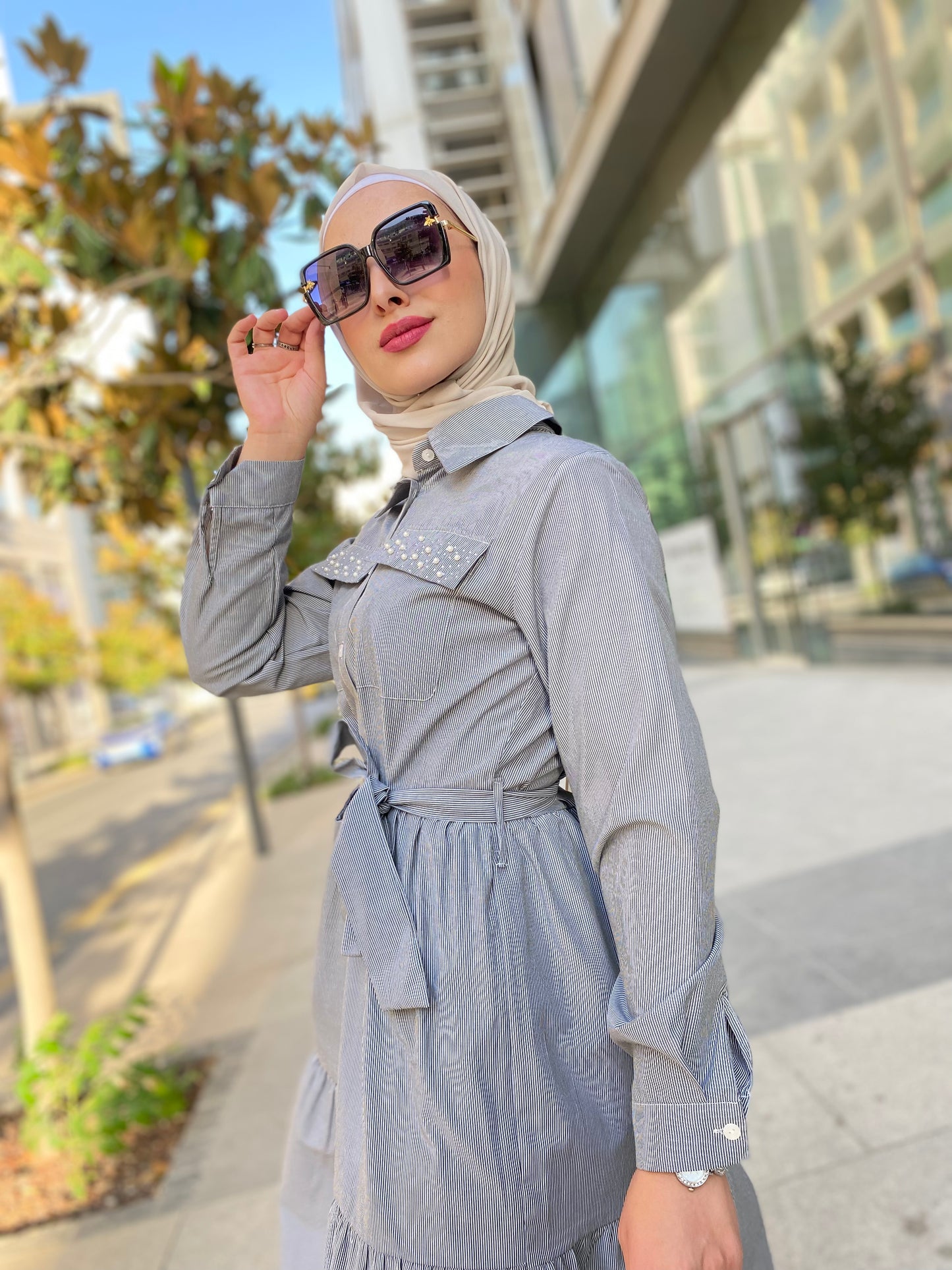 Woman in a gray outfit with sunglasses on a city street