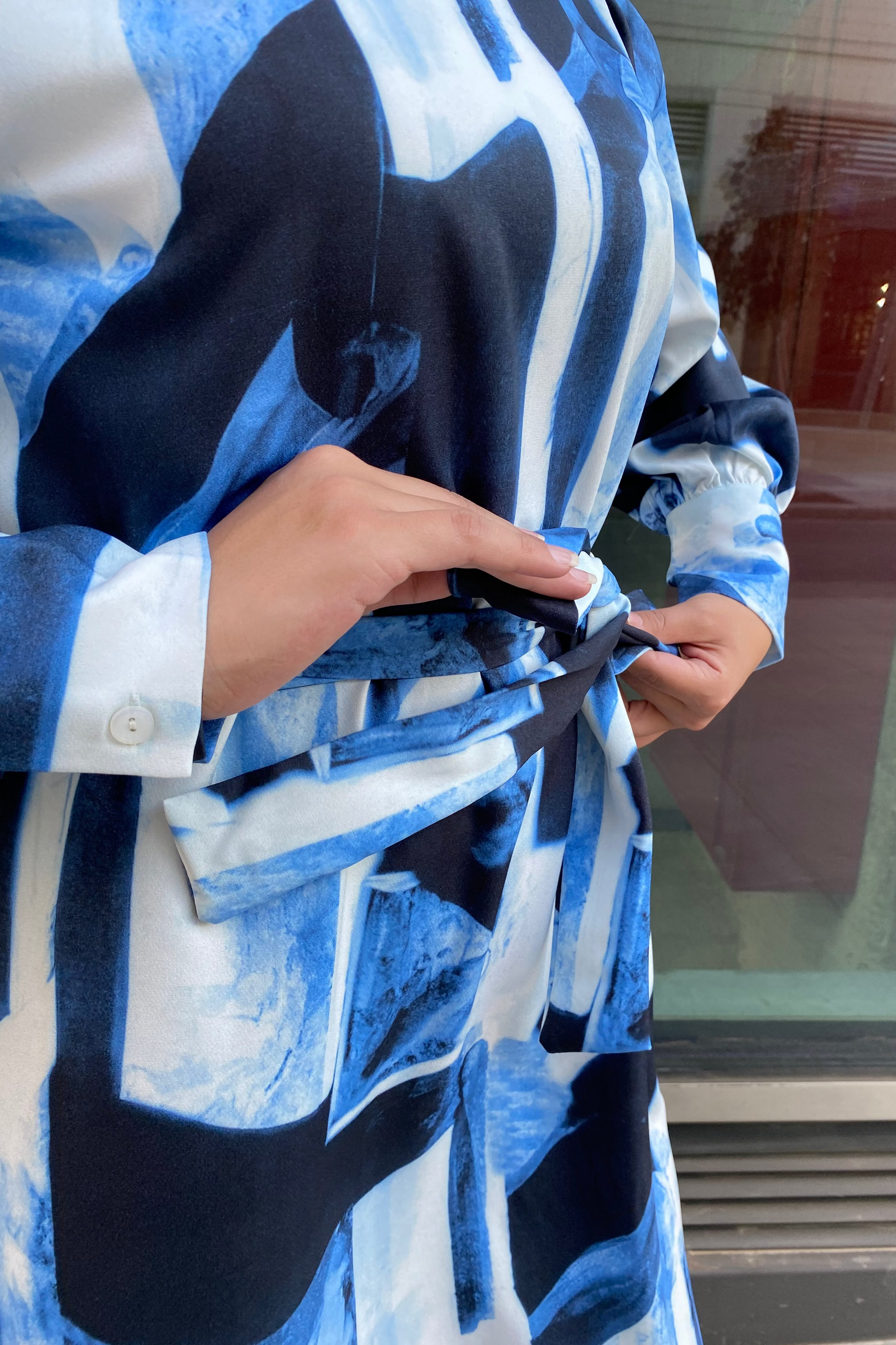 Person wearing a blue and black patterned robe with a blurred background