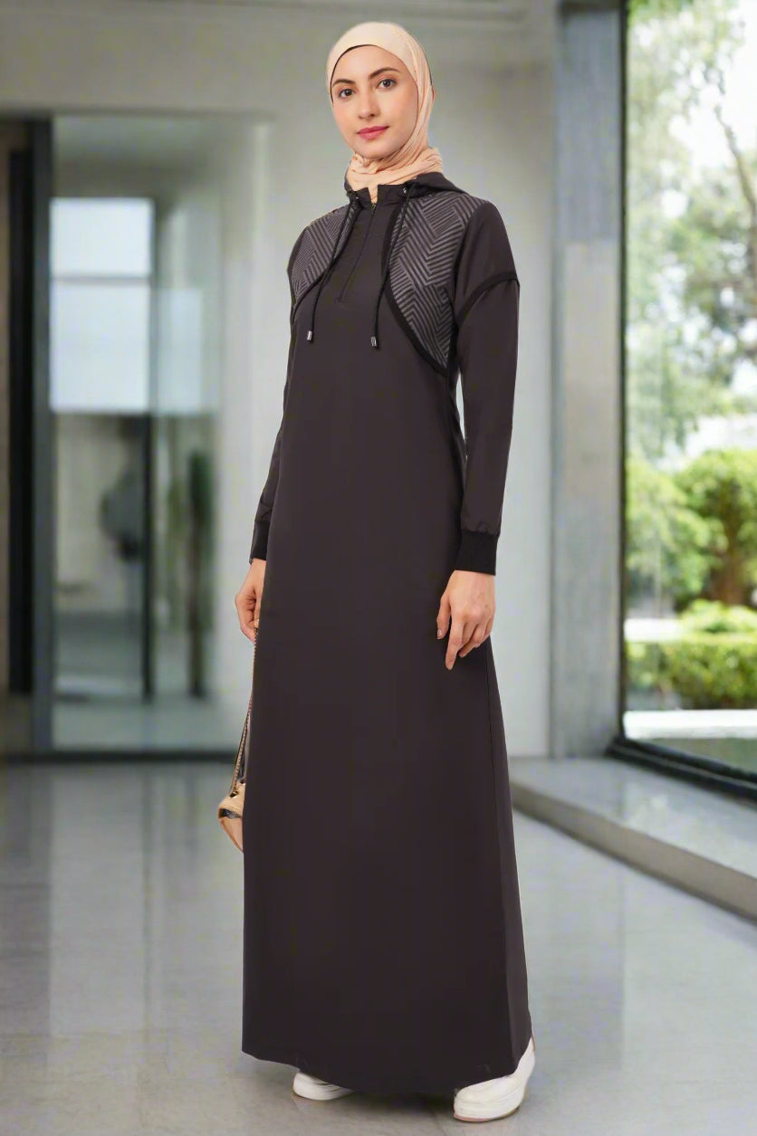 Woman wearing a black long-sleeve dress with a textured hood against a white background