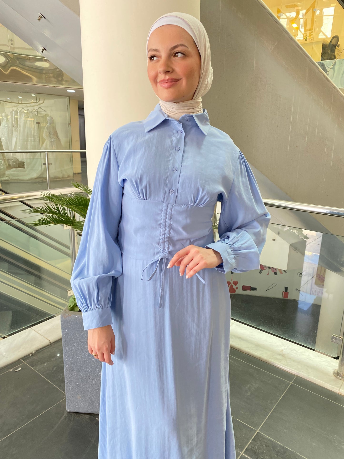Woman wearing a light blue abaya in an indoor setting