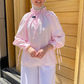 Person wearing a pink outfit with a hijab standing in front of a wooden door.