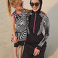 Woman and child wearing matching zebra print outfits with black hijabs on a white background