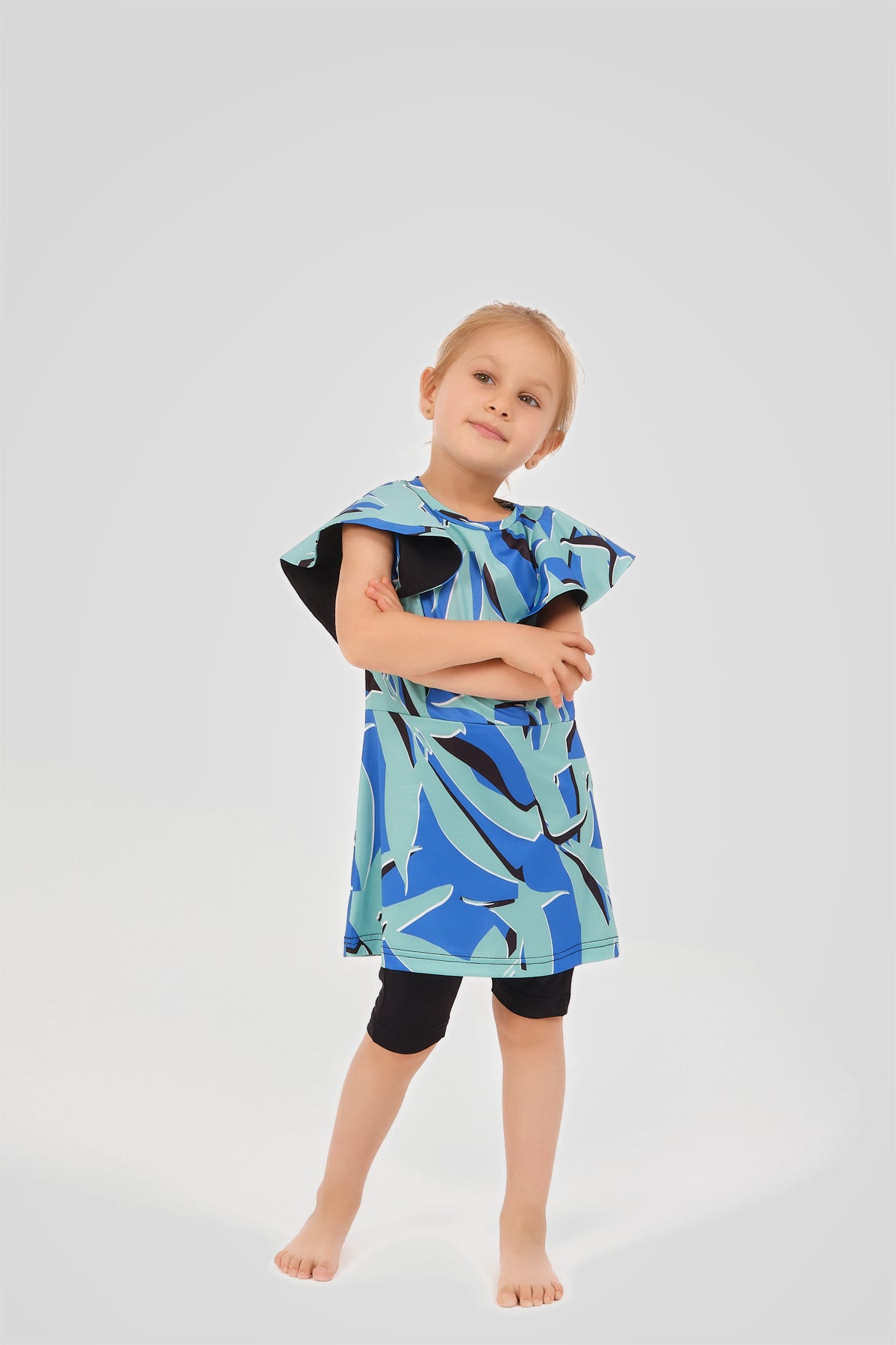 Child wearing a blue and green patterned dress on a light gray background