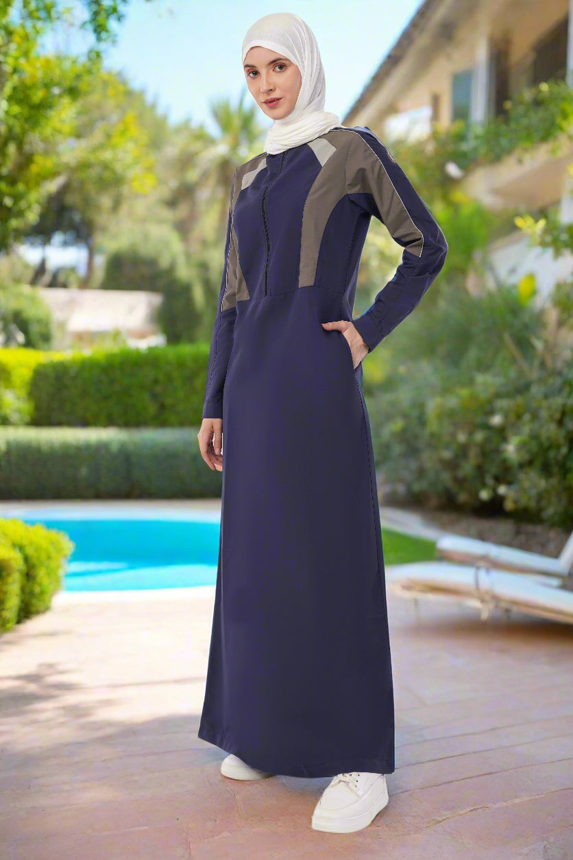 Woman wearing a long dark blue dress with gray accents on a white background