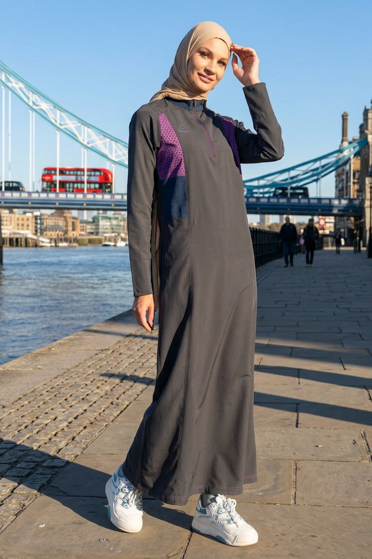 Woman in a long, dark gray dress with purple accents standing in front of Tower Bridge.