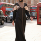 Woman in a black and beige outfit walking on a city street with red double-decker buses in the background.