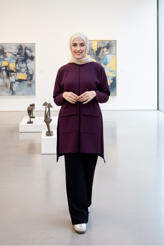 Woman in a purple outfit standing in an art gallery with sculptures and paintings on the wall.