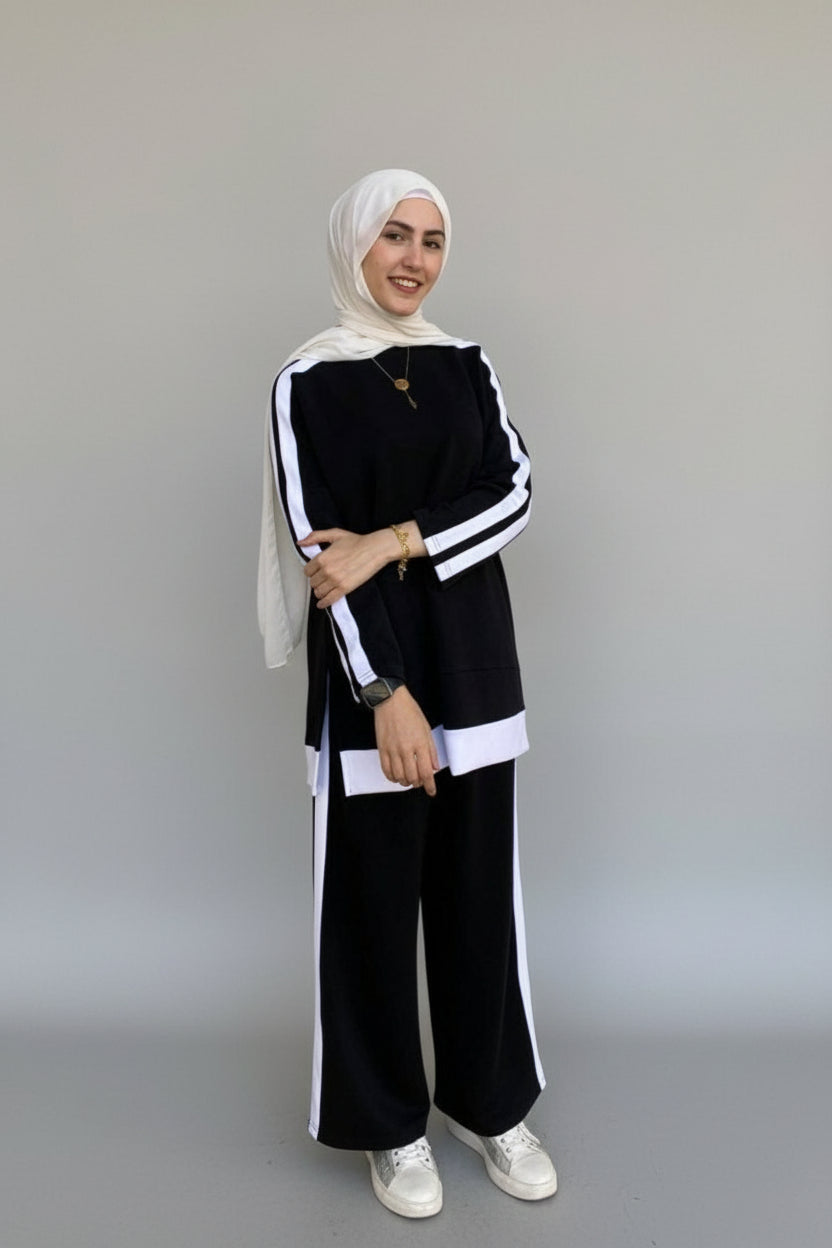 Woman in a black and white outfit standing in front of a gray door.