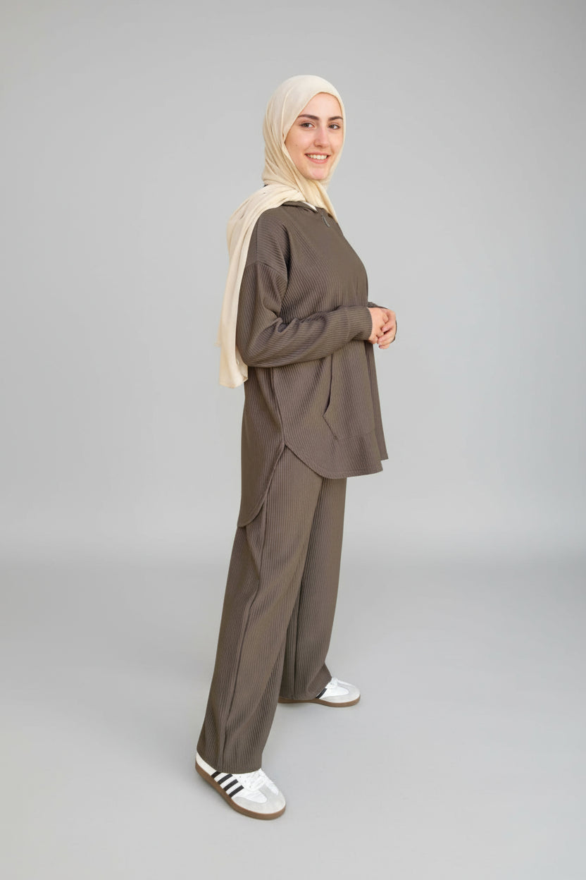 Woman in a brown outfit standing in front of a light blue door.