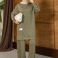 A woman wearing a matching green lounge set with a long-sleeve top and wide-leg pants, styled with a light beige hijab, a small cream clutch, and white sneakers, standing in front of a wooden paneled wall.