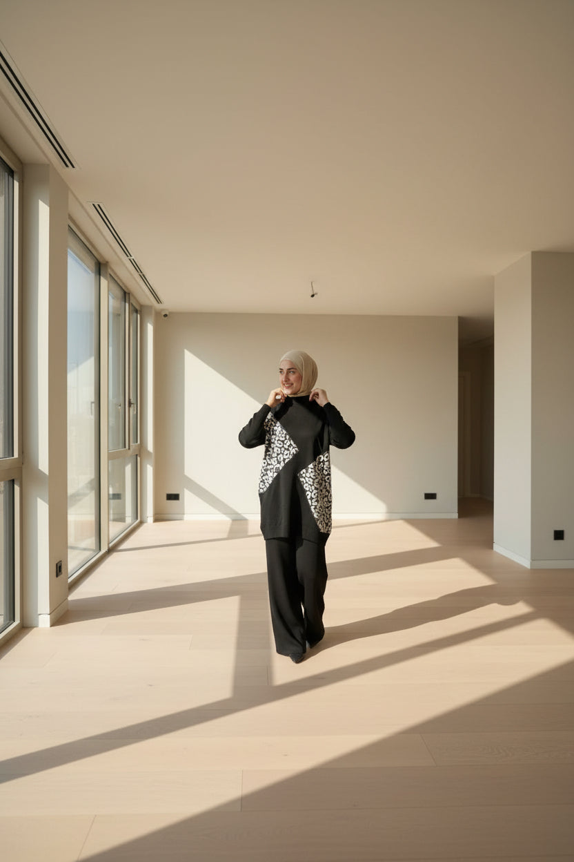 Woman wearing a black outfit with a white patterned cardigan in an outdoor setting.